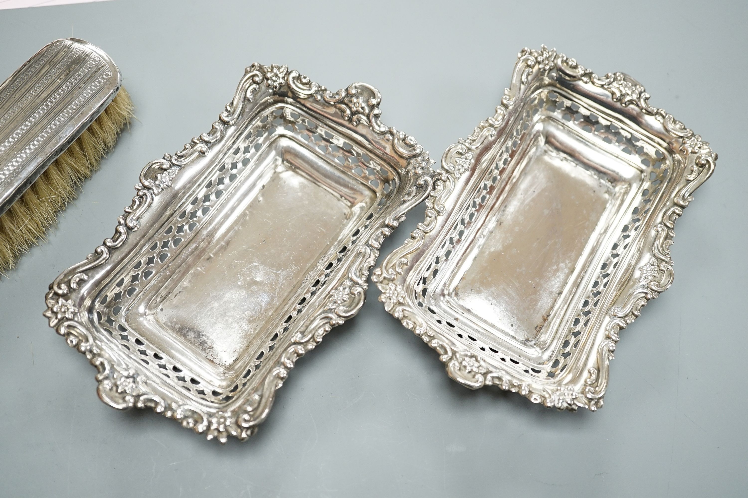 A pair of Edwardian pierced silver bonbon dishes, Chester, 1902, 16.1cm, 4.5oz, a silver and mother of pearl fruit knife, silver cased penknife and silver mounted clothes brush and a modern silver cased pocket torch.